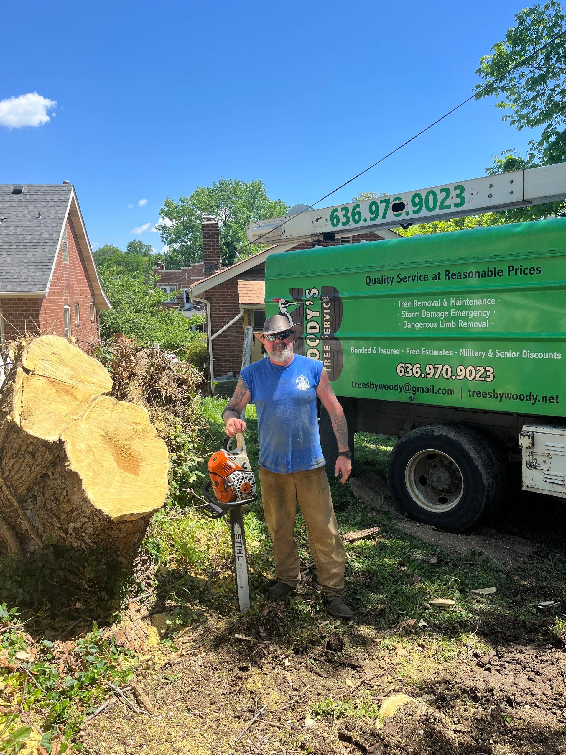 Bryan Wood, owner of B. Woody's Tree Service, with chainsaw next to the company truck in St. Charles, MO